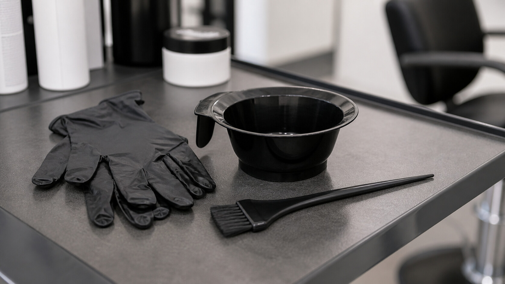 Gants, pinceau et bol de produit capillaire sur un plan de travail